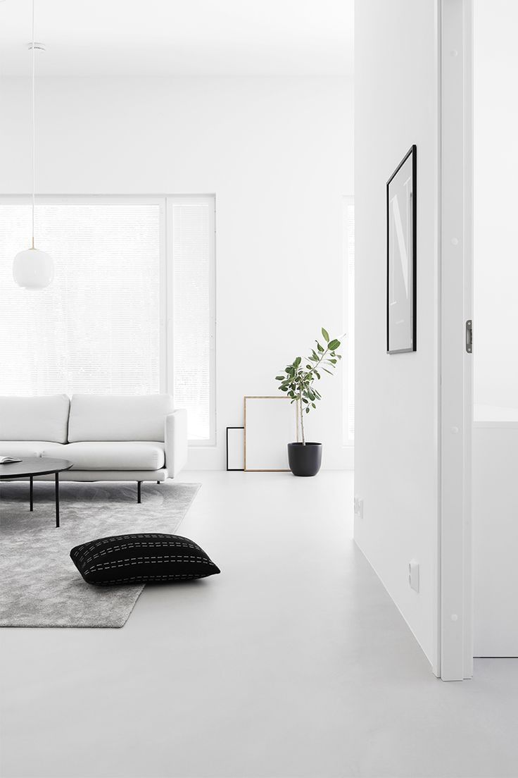 Salón de estilo minimalista con techos altos y paleta de color neutra.