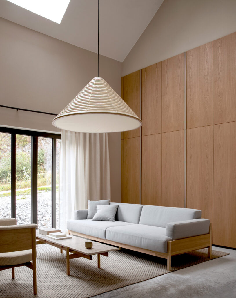 Salón de estilo japandi con sofá, mesa baja y lámpara en primer plano.